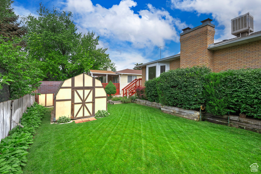 Fenced backyard featuring a storage unit