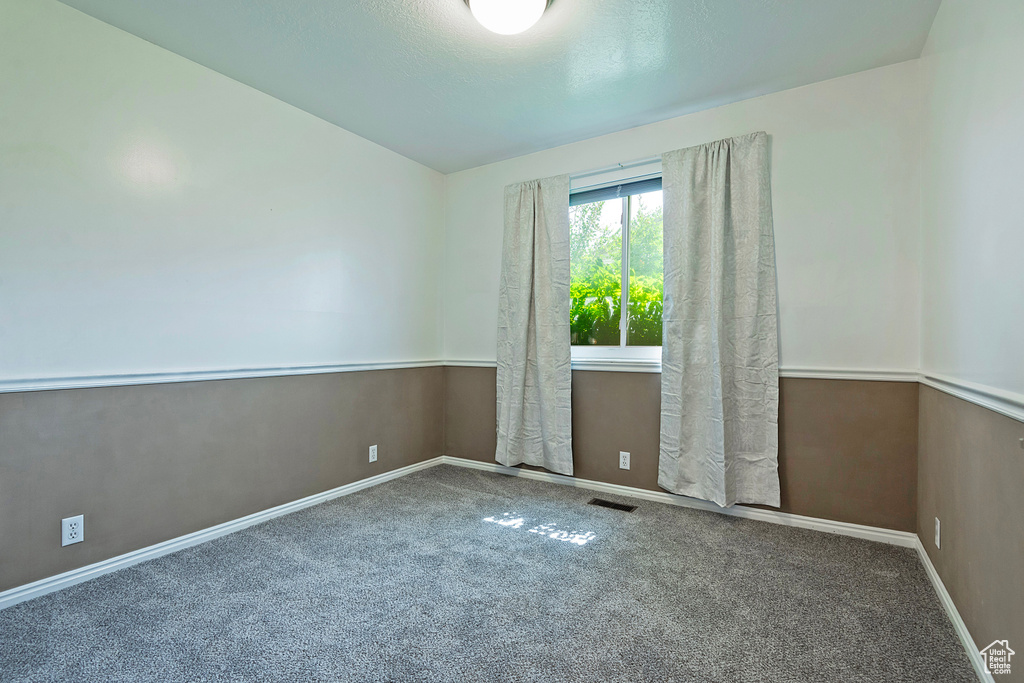 Carpeted empty room featuring vaulted ceiling and baseboards