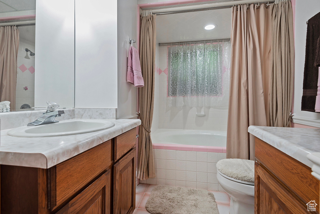 Bathroom featuring vanity, tiled shower / bath combo, and tile patterned flooring