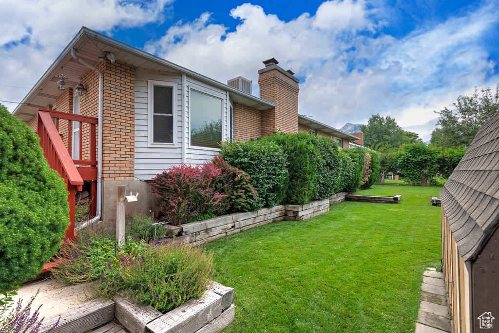 View of side of home featuring a yard, brick siding, and a chimney