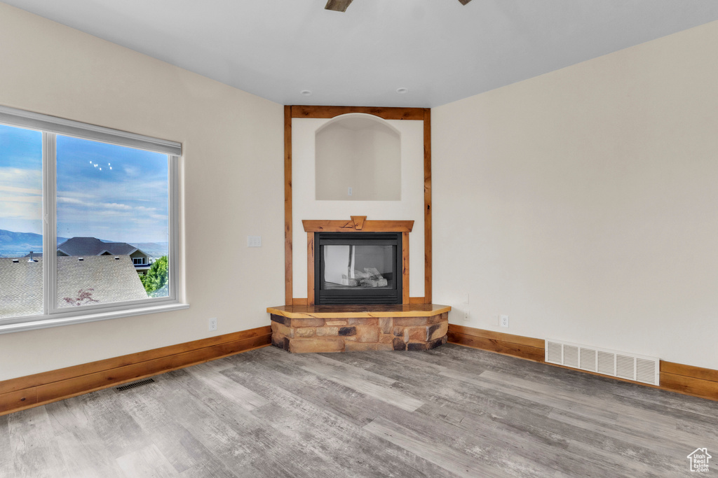 Unfurnished living room with wood finished floors, a glass covered fireplace, and healthy amount of natural light