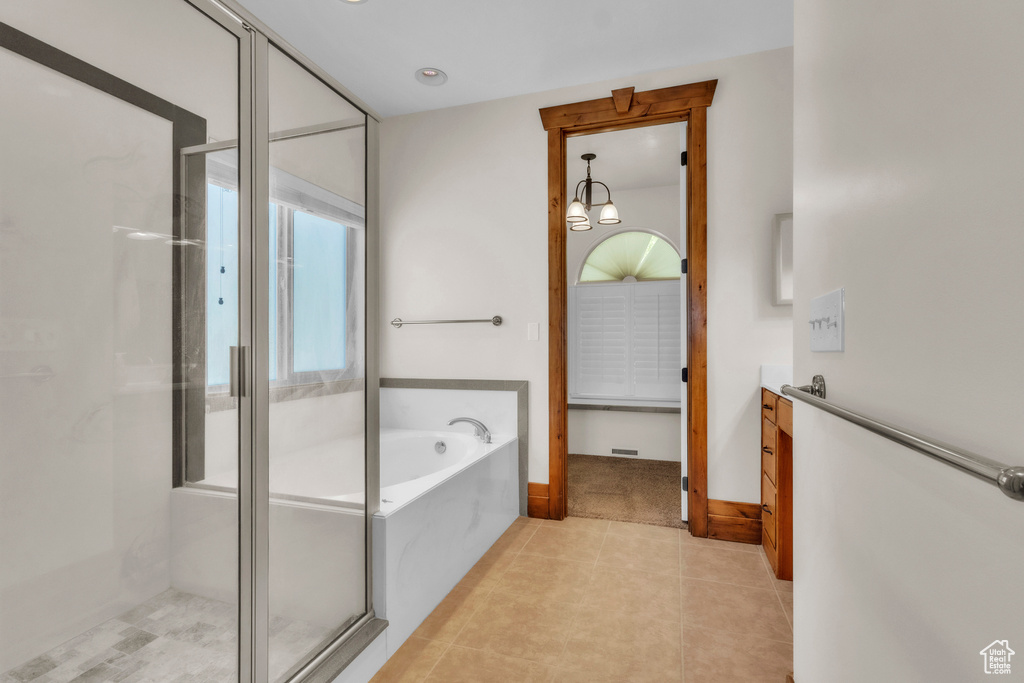 Bathroom featuring a garden tub, a shower stall, vanity, tile patterned floors, and a chandelier
