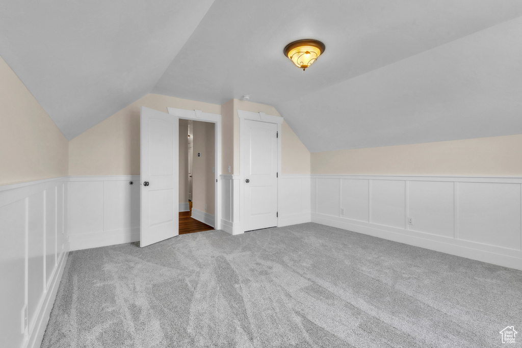 Bonus room featuring carpet floors, vaulted ceiling, a wainscoted wall, and a decorative wall