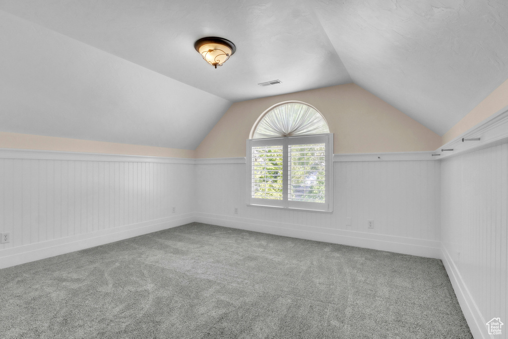 Additional living space with carpet flooring and vaulted ceiling