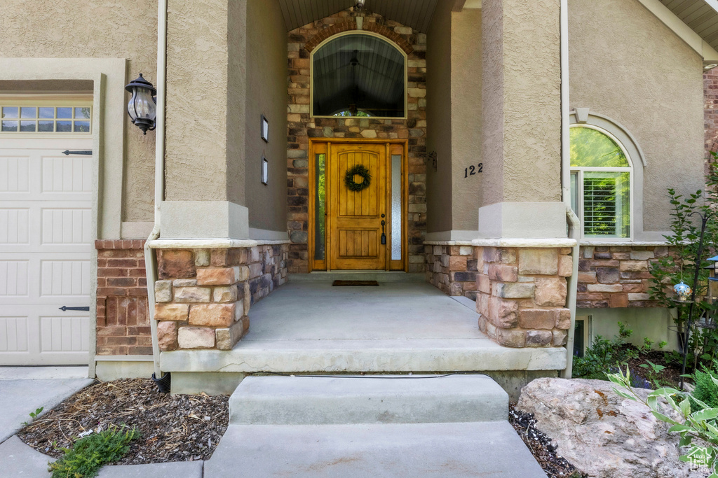 View of exterior entry featuring stucco siding, stone siding, and a garage