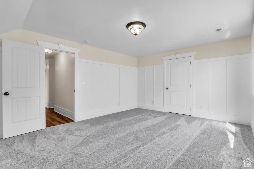 Unfurnished bedroom featuring carpet floors, multiple closets, and a decorative wall