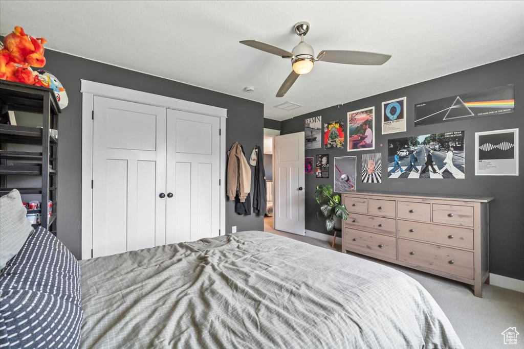 Carpeted bedroom featuring a ceiling fan and a closet