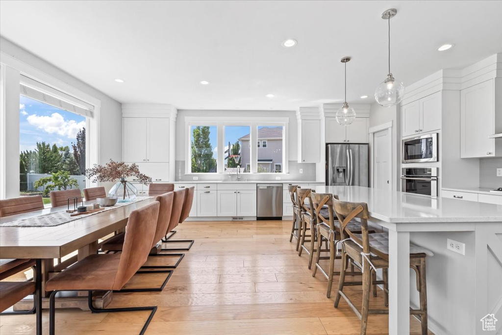 Kitchen featuring appliances with stainless steel finishes, light countertops, white cabinets, a breakfast bar, and recessed lighting