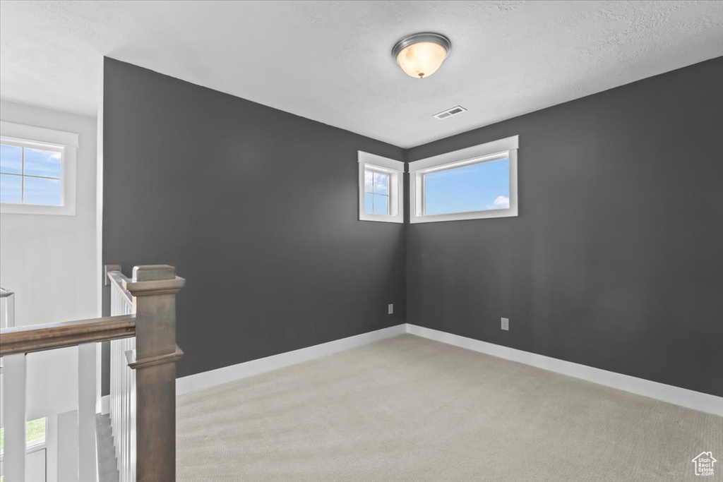 Unfurnished room featuring light carpet and baseboards
