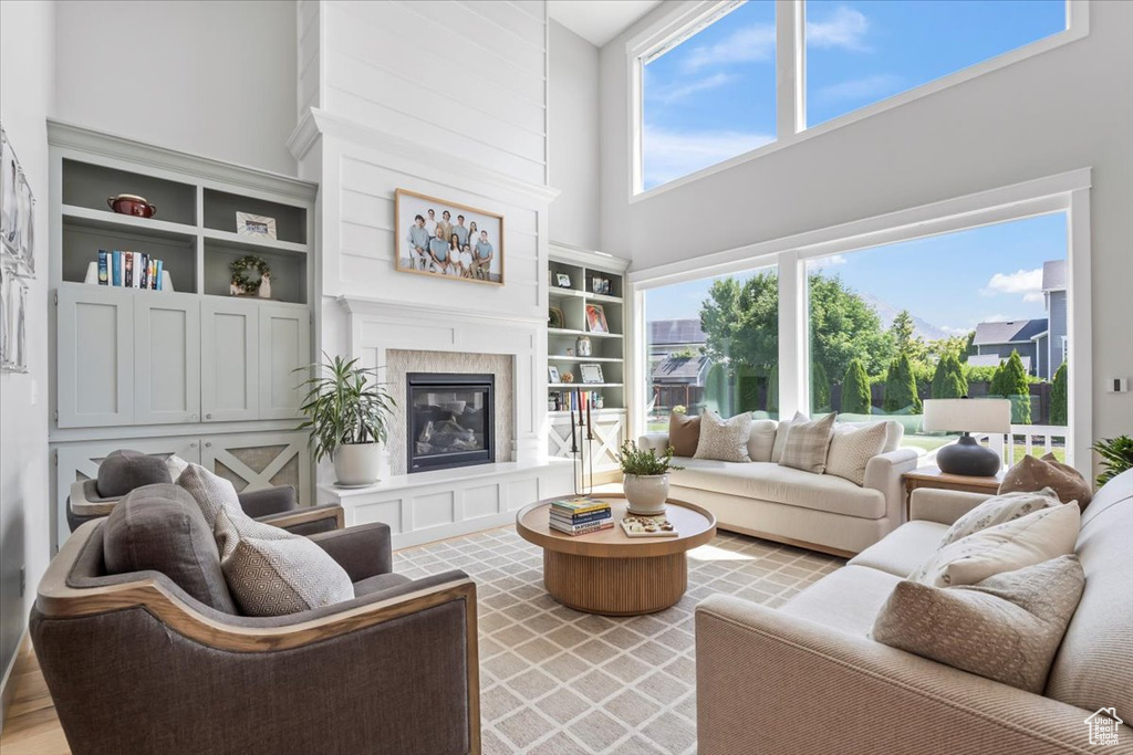 Living area with a towering ceiling, a fireplace, and built in shelves