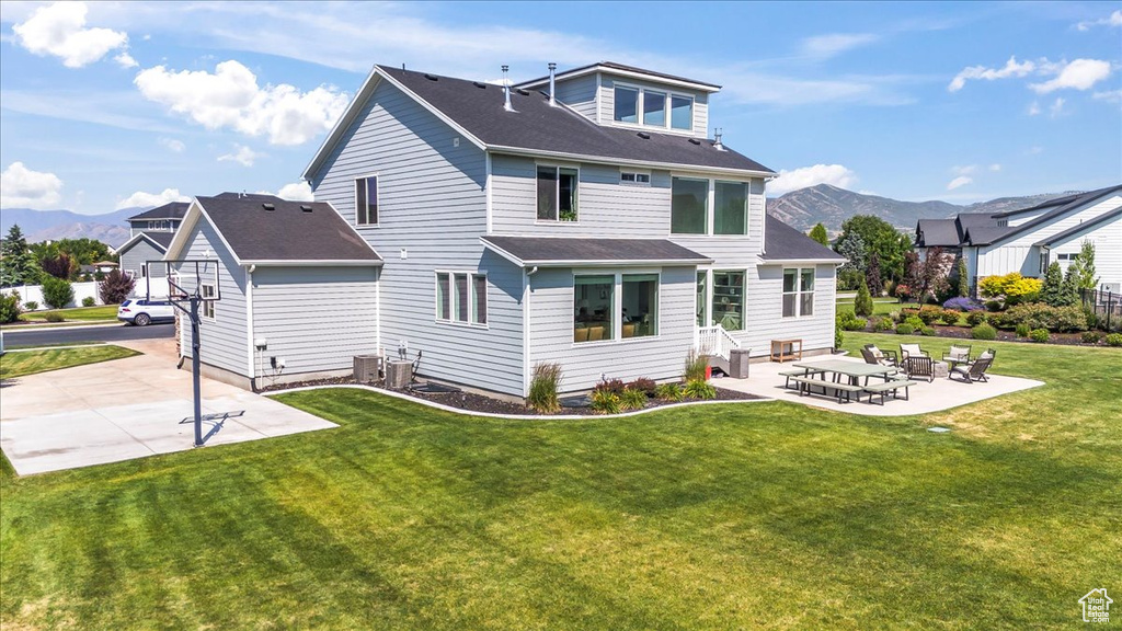 Back of property with a patio area, a mountain view, and a lawn