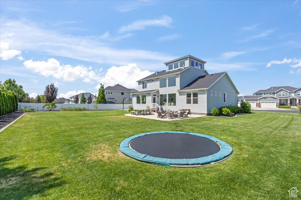 Rear view of property featuring a patio area, a trampoline, and a residential view