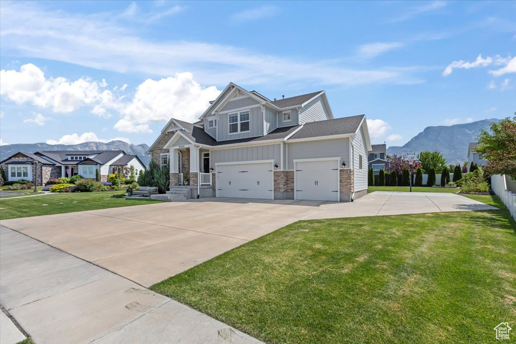 Craftsman inspired home featuring concrete driveway, a front yard, stone siding, a mountain view, and a residential view
