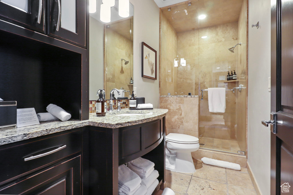 Bathroom featuring a shower stall, vanity, and stone tile floors