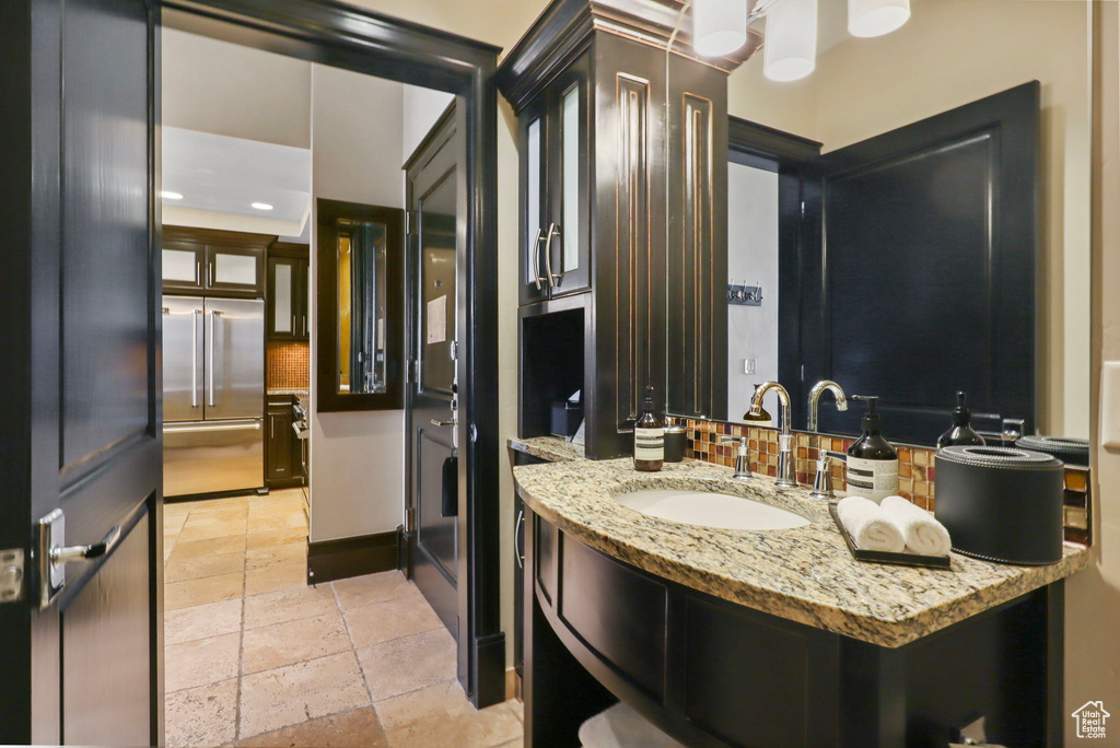 Bathroom with stone tile flooring, vanity, backsplash, and recessed lighting
