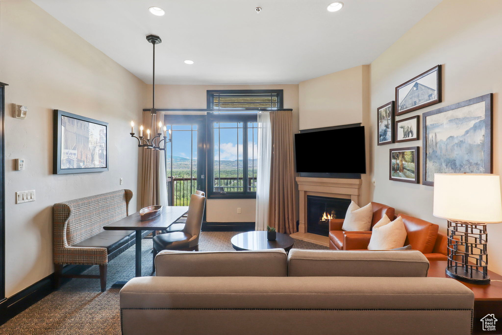 Living room featuring a warm lit fireplace, a chandelier, recessed lighting, and carpet flooring