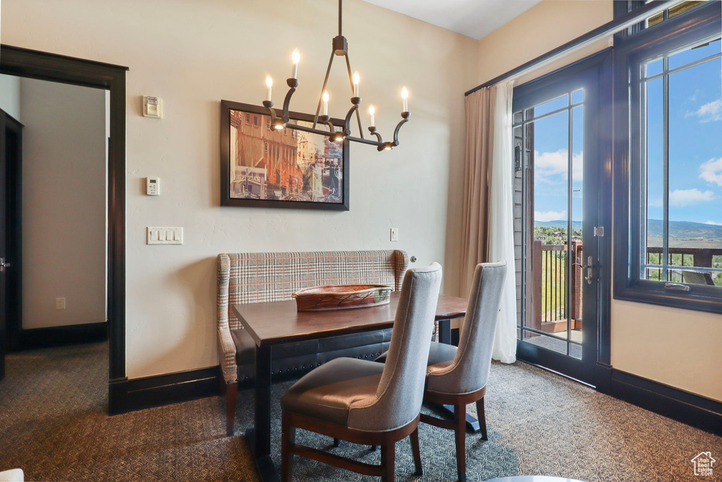 Dining space with plenty of natural light, a chandelier, and carpet flooring