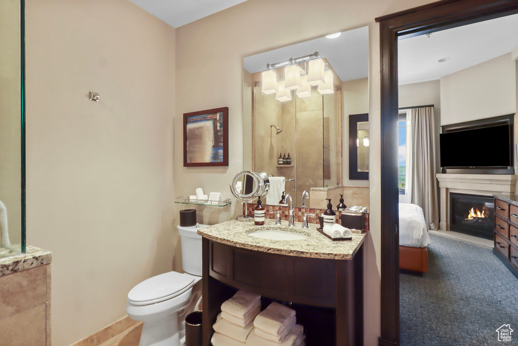 Ensuite bathroom featuring a glass covered fireplace and vanity