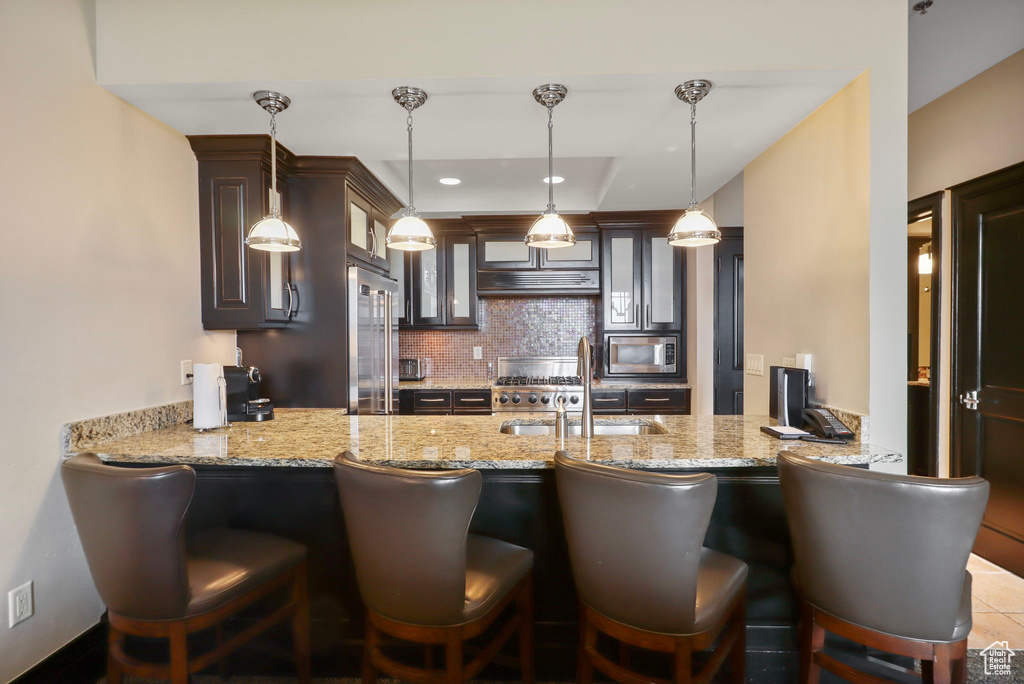 Kitchen featuring stainless steel appliances, a peninsula, tasteful backsplash, and glass insert cabinets