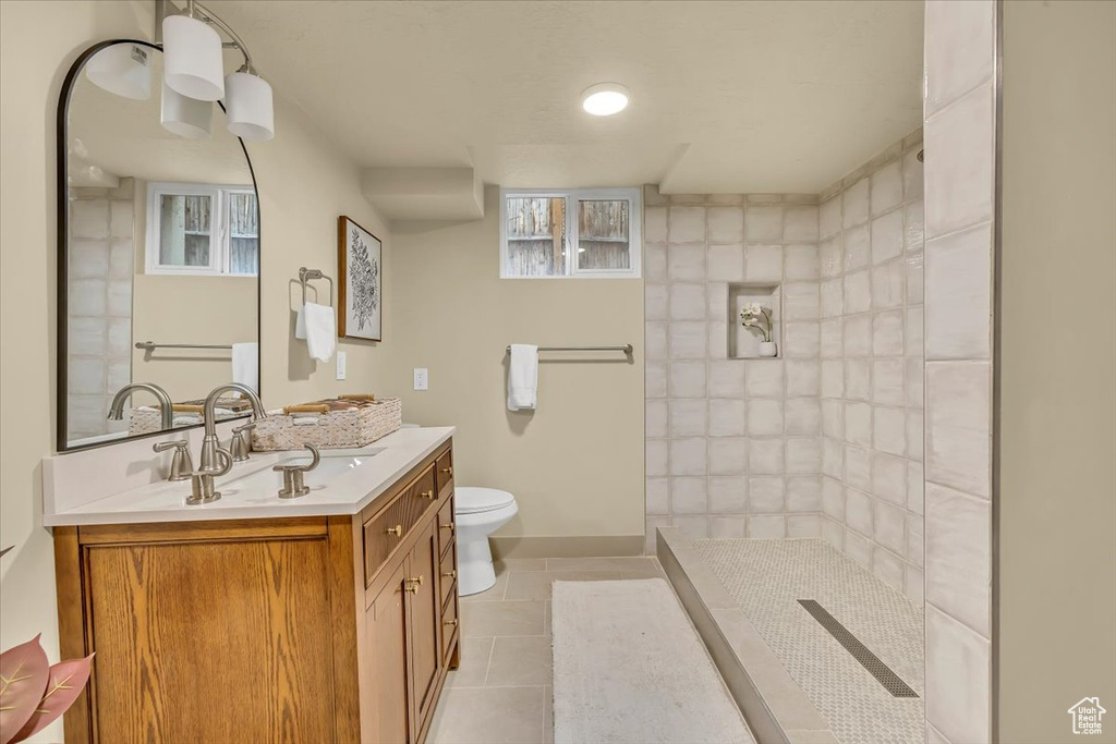 Full bathroom featuring tile patterned flooring, vanity, and a tile shower