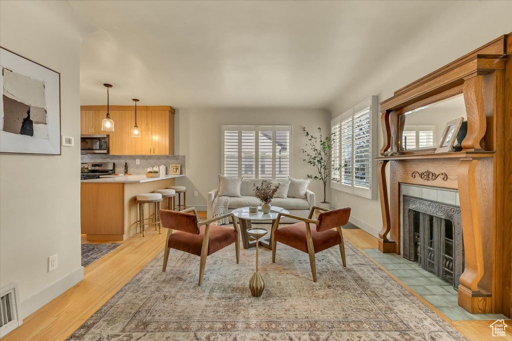 Living room with a tile fireplace and light wood-type flooring