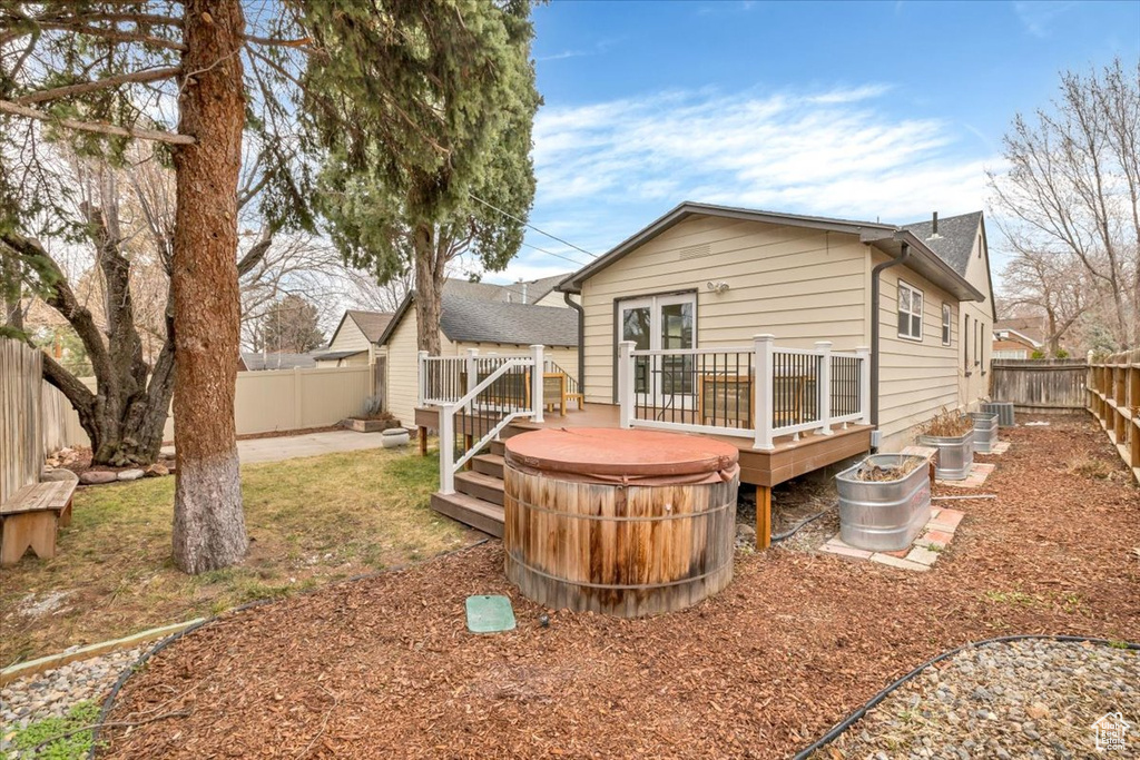 Back of house featuring a deck, a fenced backyard, and french doors
