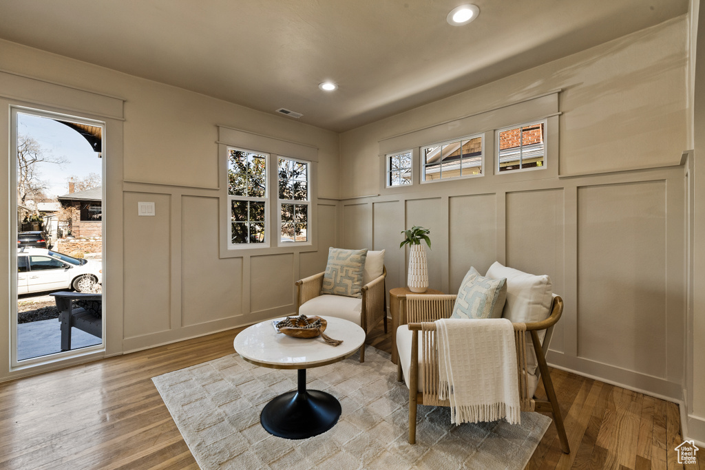 Living area featuring a decorative wall, wood finished floors, recessed lighting, and wainscoting