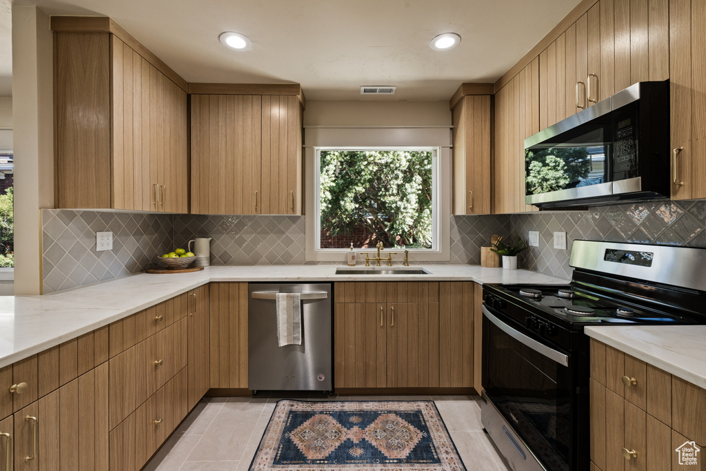 Kitchen featuring stainless steel appliances, light stone countertops, decorative backsplash, recessed lighting, and light tile patterned floors