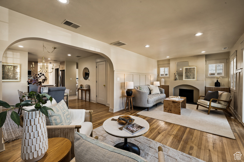 Living room featuring arched walkways, wood-type flooring, recessed lighting, and a chandelier