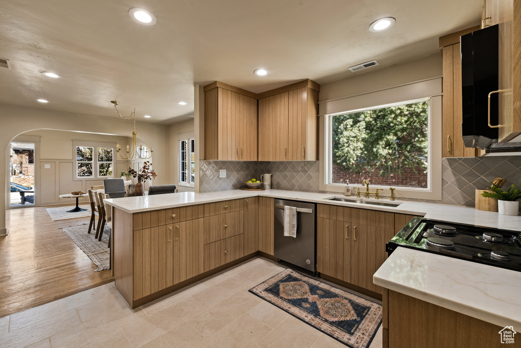 Kitchen featuring stainless steel dishwasher, a peninsula, arched walkways, recessed lighting, and decorative backsplash
