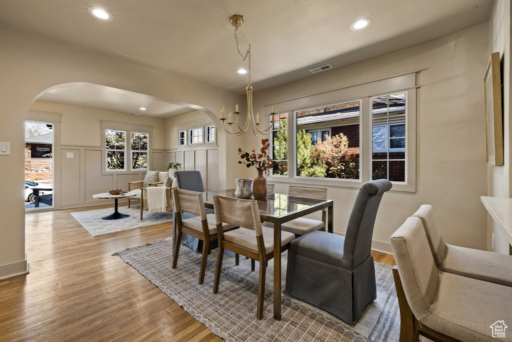 Dining space with arched walkways, wood finished floors, and recessed lighting