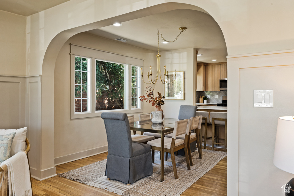 Dining area featuring arched walkways, light wood-style flooring, and recessed lighting