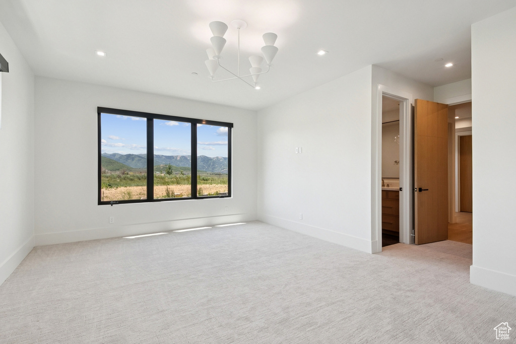 Empty room featuring a chandelier, light colored carpet, recessed lighting, and a mountain view