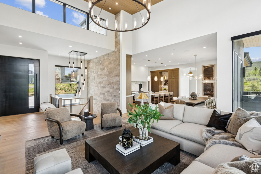 Living area featuring a chandelier, a high ceiling, wood finished floors, and recessed lighting