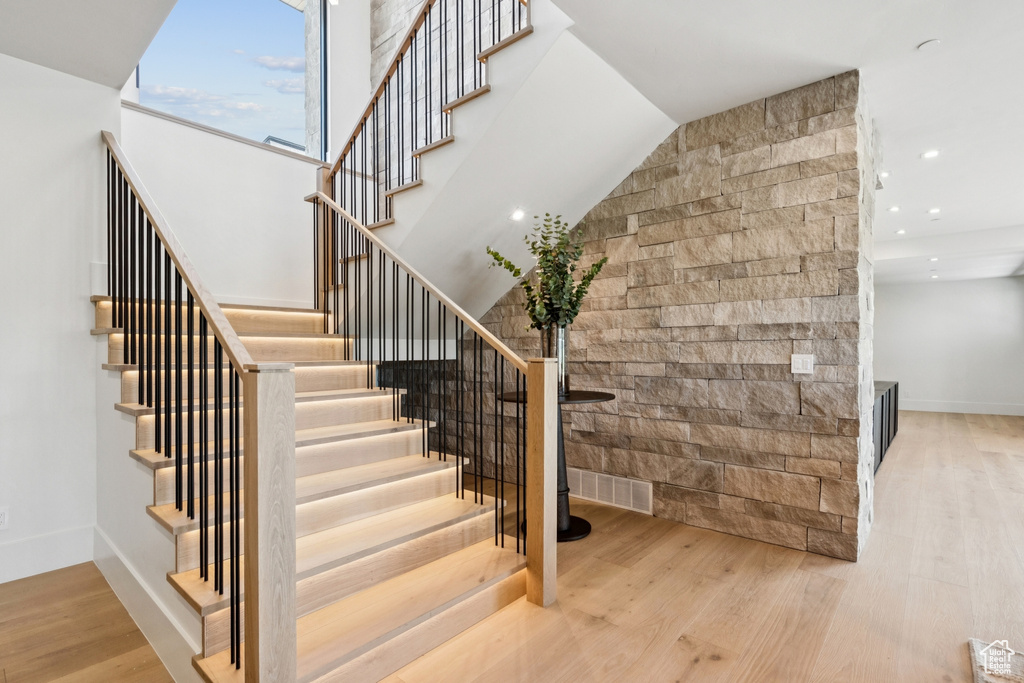 Staircase with wood finished floors and recessed lighting