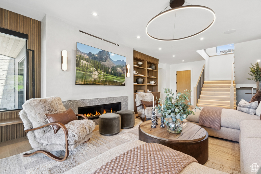 Living room with a glass covered fireplace, stairway, recessed lighting, and wood finished floors
