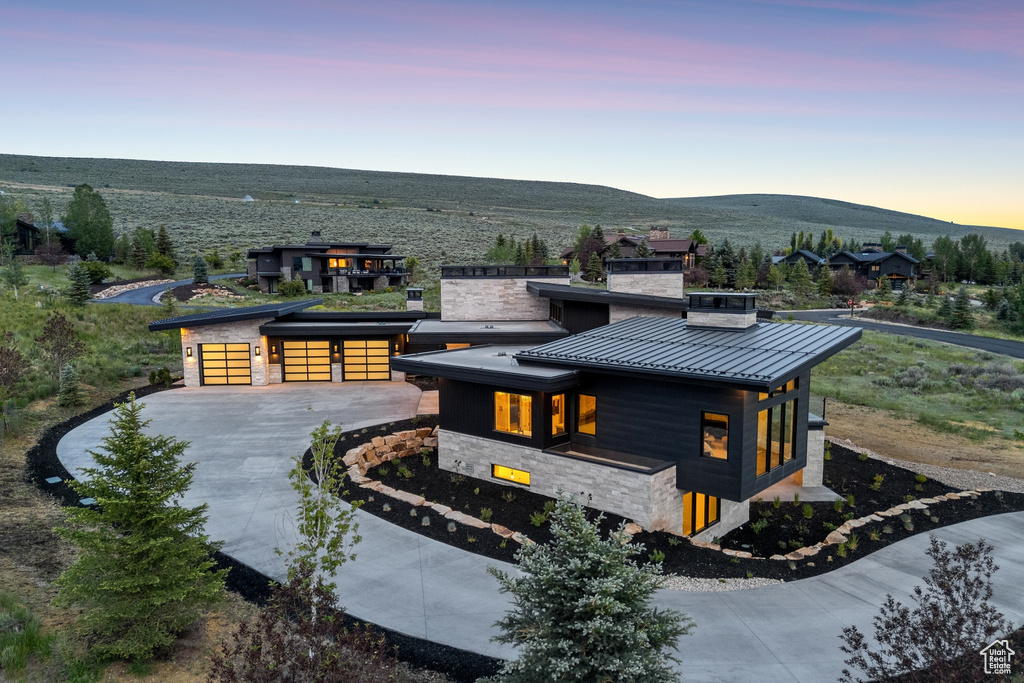 Contemporary home with a standing seam roof, stone siding, a mountain view, a metal roof, and driveway