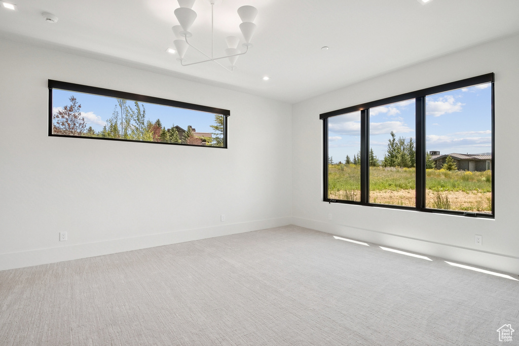 Carpeted spare room with a chandelier, healthy amount of natural light, recessed lighting, and a smoke detector