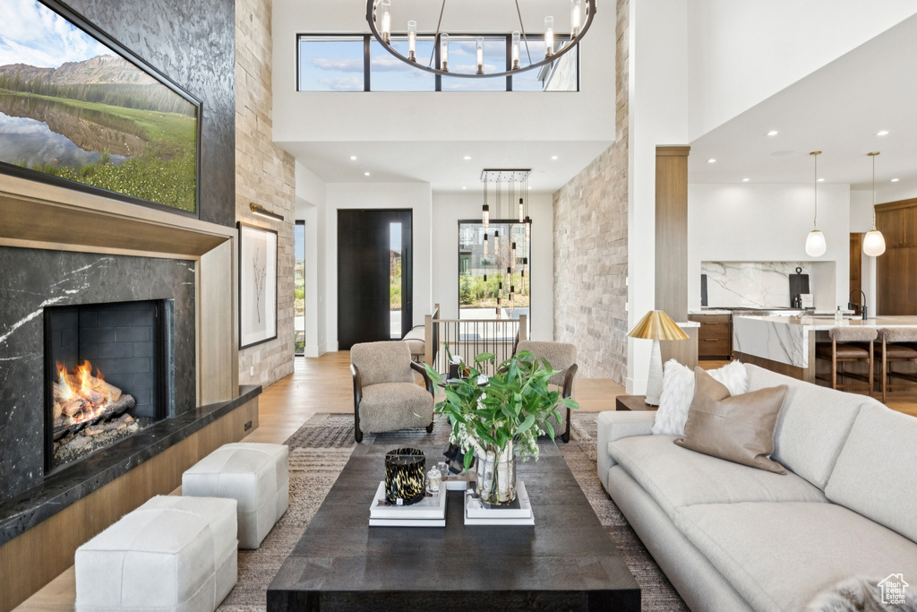 Living room with a high ceiling, wood finished floors, a fireplace, a chandelier, and recessed lighting