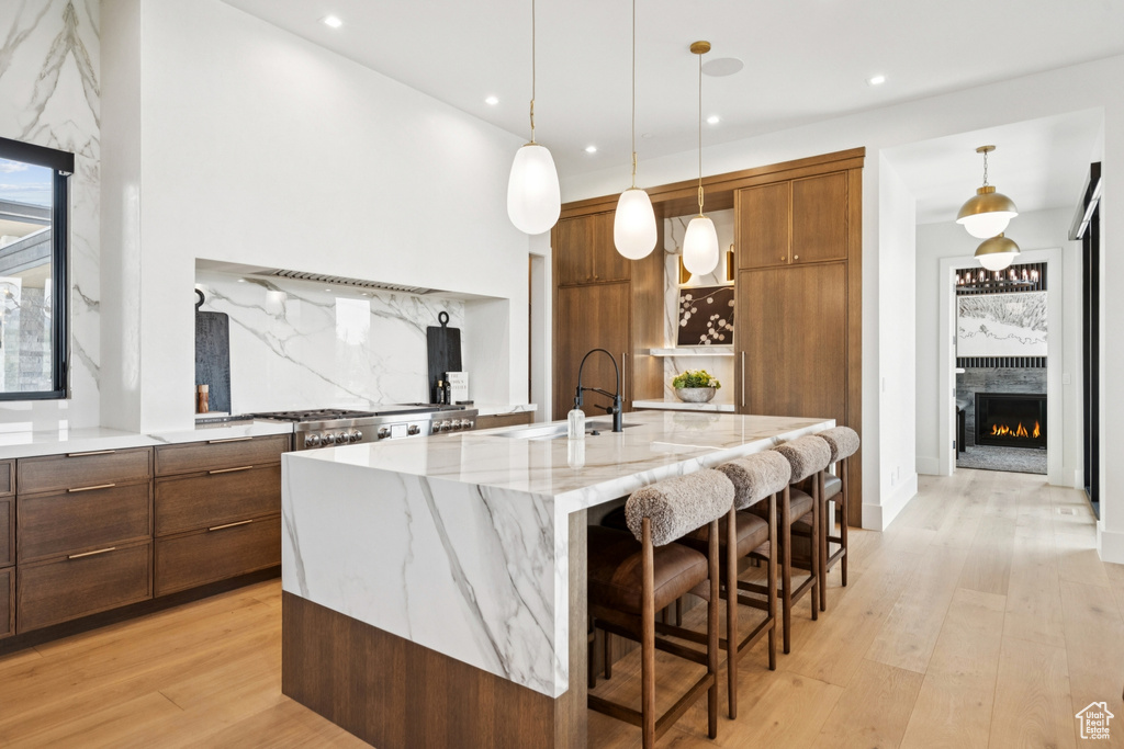 Kitchen featuring modern cabinets, light wood-style floors, a spacious island, a lit fireplace, and recessed lighting