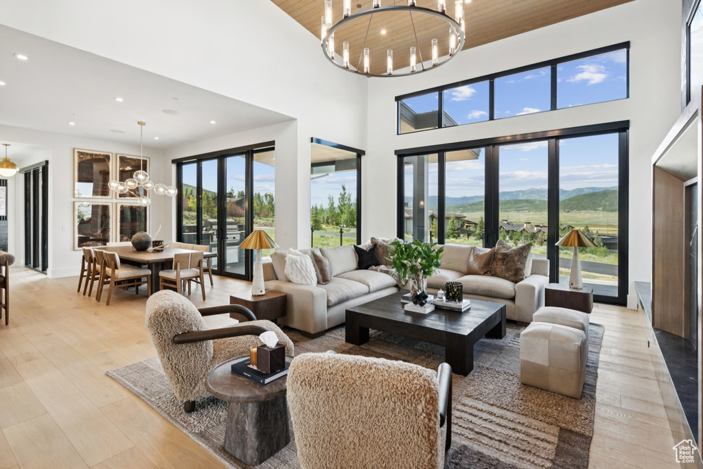 Living room featuring a chandelier, recessed lighting, a towering ceiling, light wood finished floors, and wooden ceiling