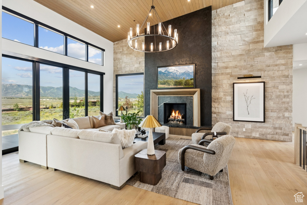 Living room featuring wooden ceiling, high vaulted ceiling, hardwood / wood-style floors, a fireplace, and a chandelier