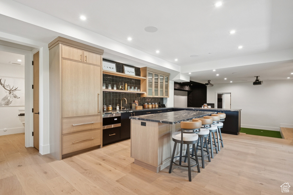 Indoor wet bar with backsplash, light wood-style flooring, and recessed lighting