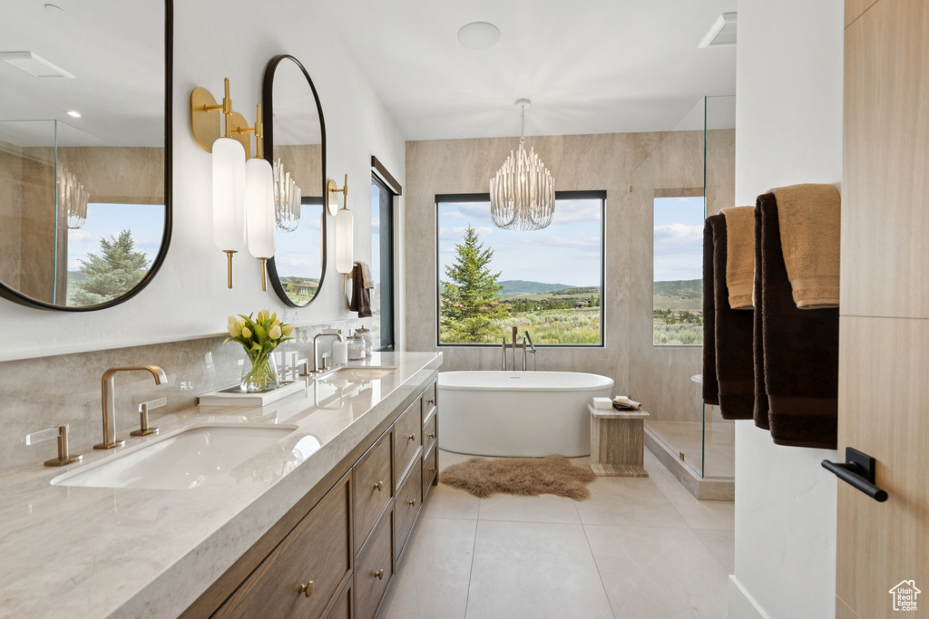 Bathroom featuring tile patterned floors, a soaking tub, double vanity, an enclosed shower, and a chandelier