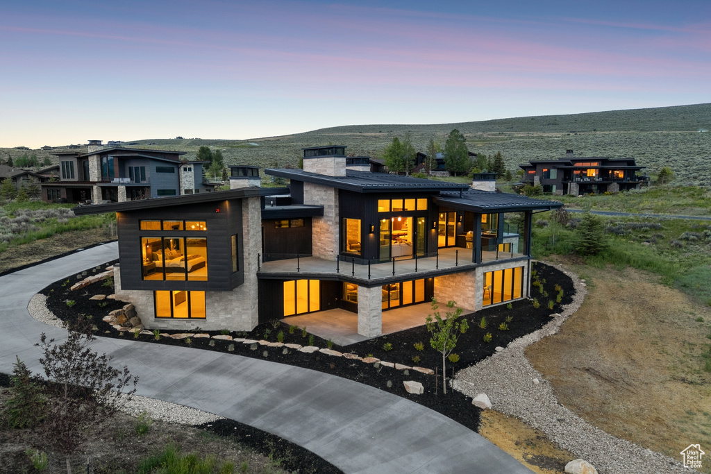 Contemporary house featuring a balcony, a chimney, stone siding, and a mountain view
