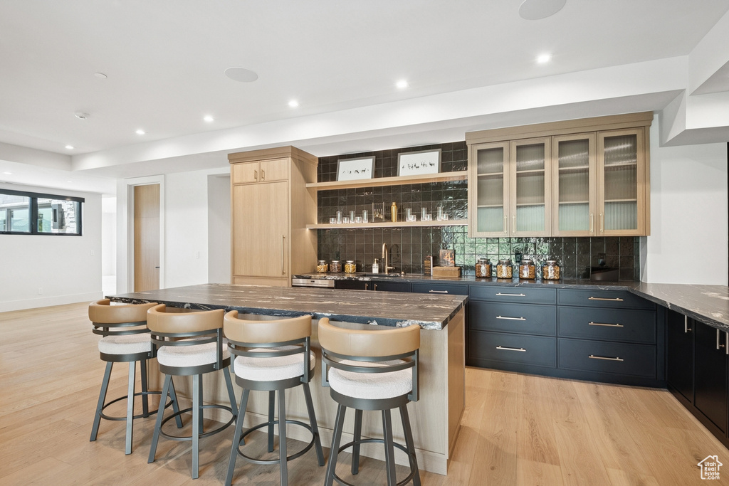 Indoor wet bar featuring tasteful backsplash, light wood-style flooring, and recessed lighting