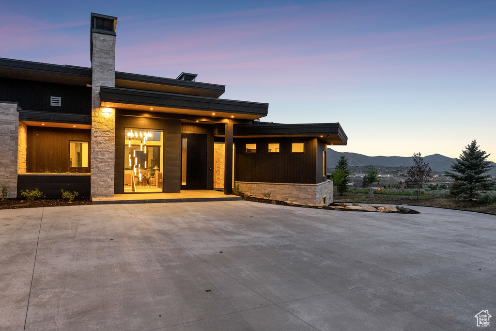 View of front of property featuring stone siding, a mountain view, and a chimney