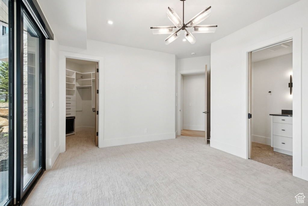 Unfurnished bedroom featuring multiple windows, light colored carpet, and a spacious closet