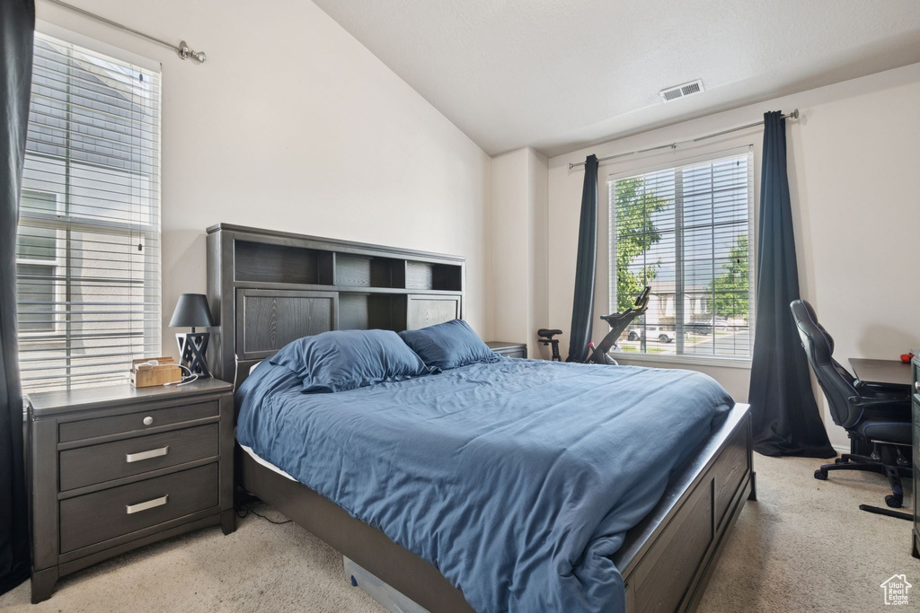Bedroom with vaulted ceiling, light colored carpet, and an office area