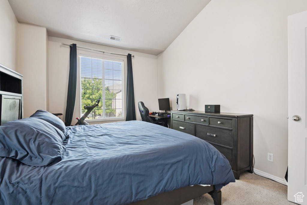 Bedroom with light colored carpet and lofted ceiling